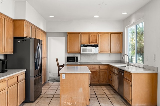 kitchen featuring appliances with stainless steel finishes, a center island, light countertops, a sink, and recessed lighting