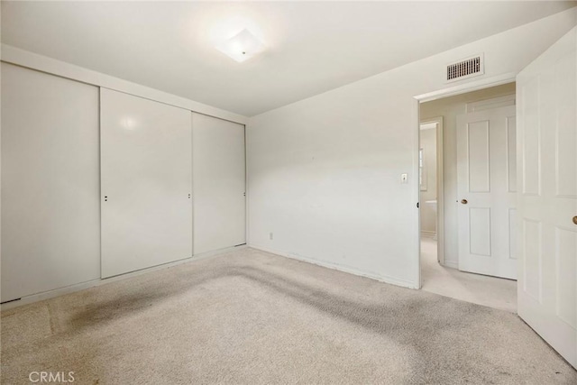 unfurnished bedroom featuring light carpet, a closet, and visible vents