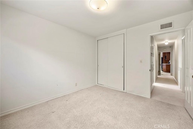 unfurnished bedroom with baseboards, a closet, visible vents, and light colored carpet