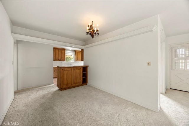 interior space with light carpet, baseboards, a sink, and an inviting chandelier