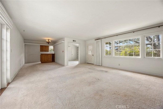 unfurnished living room featuring baseboards, stairs, visible vents, and light colored carpet