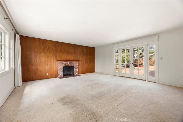 unfurnished living room with wood walls, plenty of natural light, a fireplace, and carpet flooring