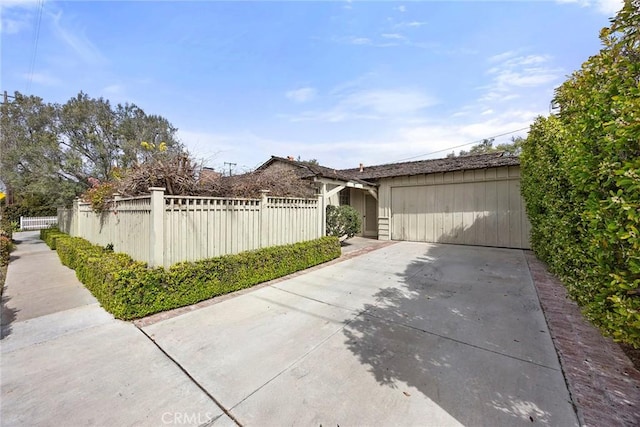 exterior space featuring a fenced front yard and concrete driveway