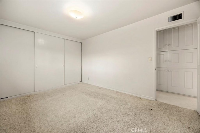 unfurnished bedroom with light carpet, baseboards, visible vents, and a closet