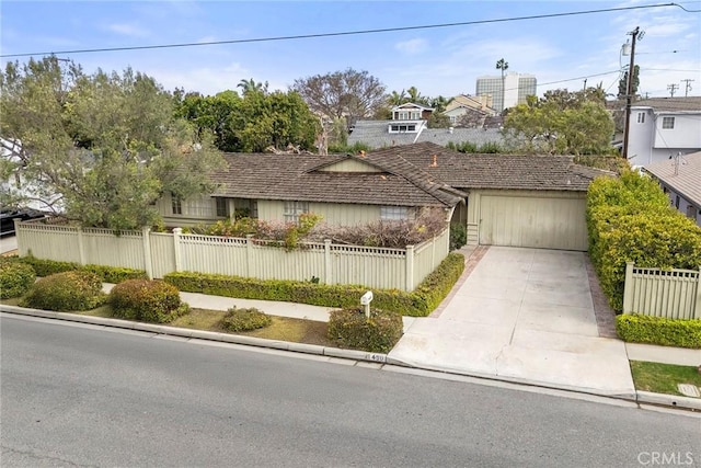 view of front facade featuring a fenced front yard, concrete driveway, and an attached garage