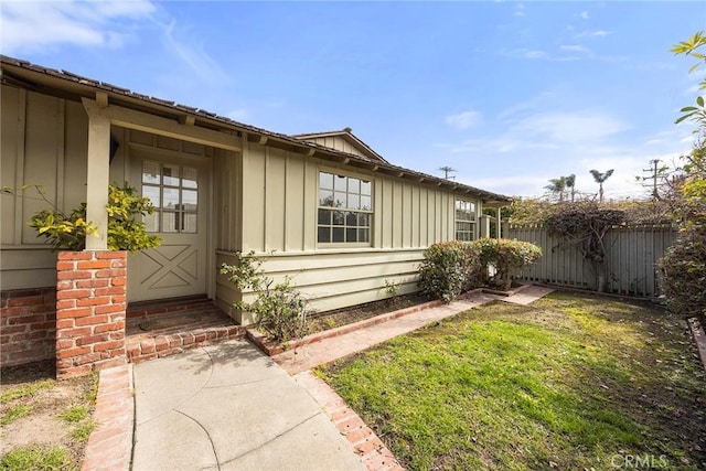 view of side of property featuring a yard, board and batten siding, and fence