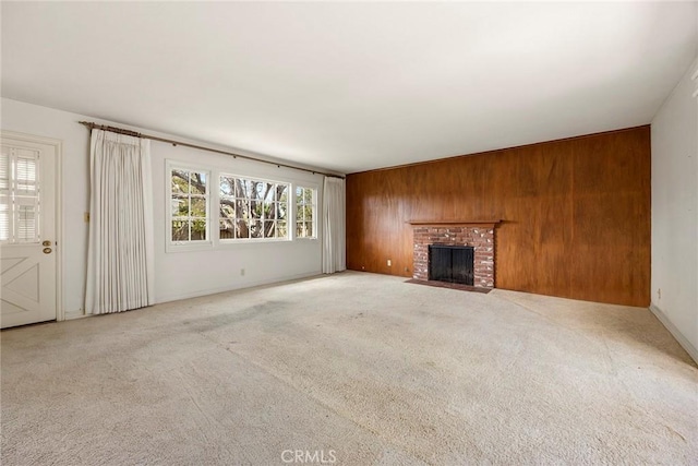 unfurnished living room with wood walls, a brick fireplace, and carpet flooring