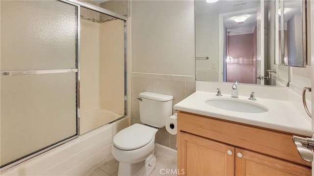 full bathroom with combined bath / shower with glass door, vanity, toilet, and tile patterned floors