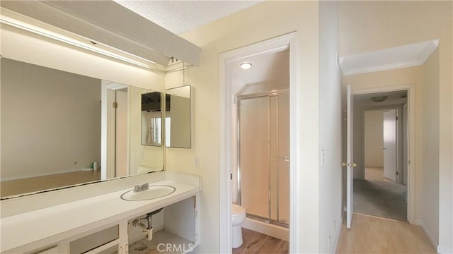 full bath featuring a sink, wood finished floors, a shower stall, and toilet