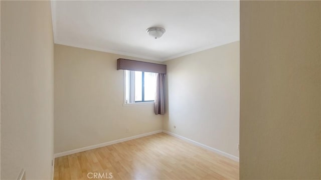 empty room featuring ornamental molding, baseboards, and wood finished floors