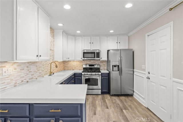 kitchen featuring blue cabinets, white cabinetry, appliances with stainless steel finishes, and a sink