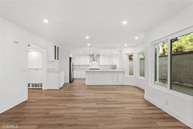 unfurnished living room featuring light wood-type flooring, baseboards, a sink, and recessed lighting