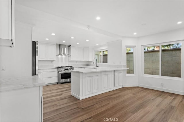 kitchen featuring appliances with stainless steel finishes, light countertops, a sink, and wall chimney exhaust hood