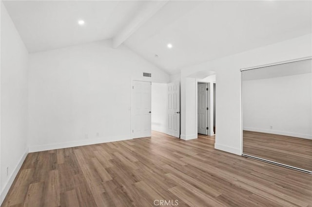 unfurnished bedroom featuring baseboards, visible vents, wood finished floors, and beamed ceiling