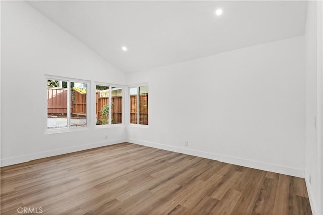 empty room with high vaulted ceiling, recessed lighting, baseboards, and wood finished floors