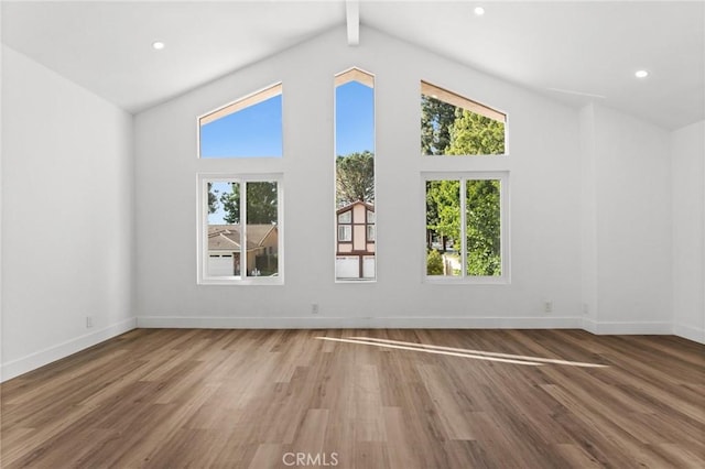 spare room with plenty of natural light, baseboards, wood finished floors, and beamed ceiling