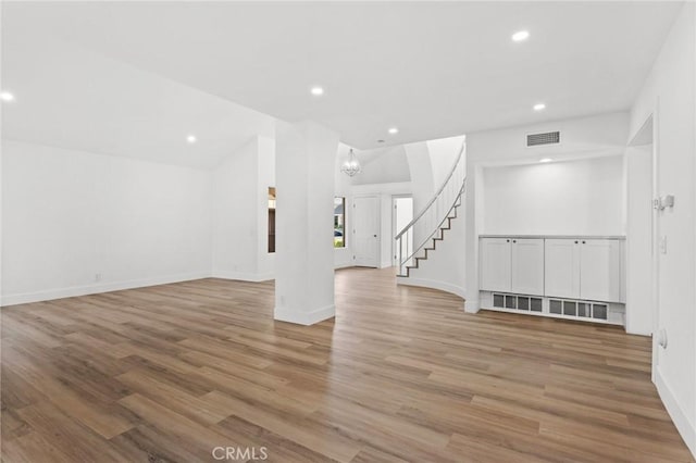 empty room featuring recessed lighting, wood finished floors, visible vents, and stairs