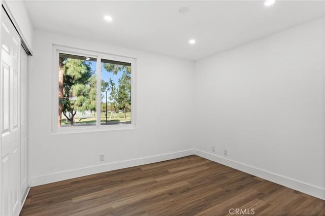 spare room featuring baseboards, dark wood finished floors, and recessed lighting