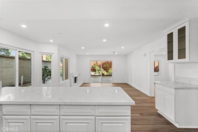 kitchen with white cabinets, wood finished floors, light stone countertops, and recessed lighting
