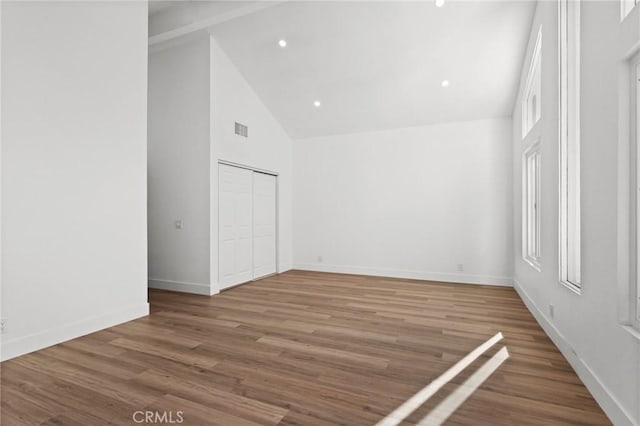 unfurnished bedroom featuring baseboards, visible vents, wood finished floors, high vaulted ceiling, and recessed lighting