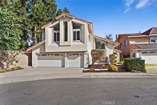 view of front of house with an attached garage, a tiled roof, concrete driveway, and stucco siding