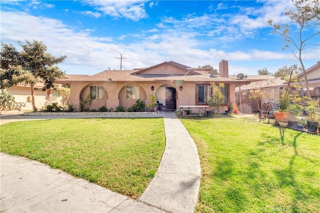 view of front of property with stucco siding, a chimney, a front lawn, and fence