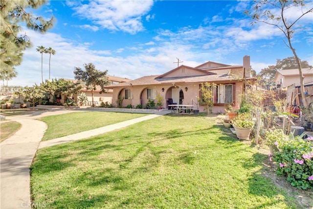 view of front of house featuring stucco siding, a chimney, a front yard, and fence