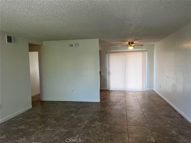 unfurnished room with visible vents, baseboards, dark tile patterned floors, and a ceiling fan