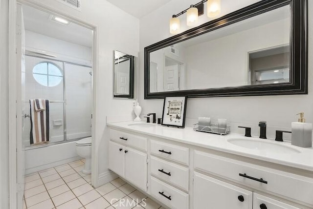 full bath featuring double vanity, a sink, toilet, and tile patterned floors