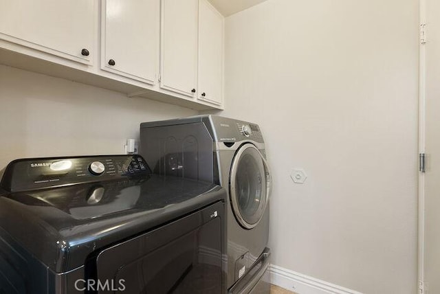 laundry area featuring cabinet space, baseboards, and washer and dryer