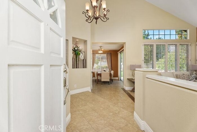 foyer featuring a chandelier, high vaulted ceiling, baseboards, and light tile patterned floors