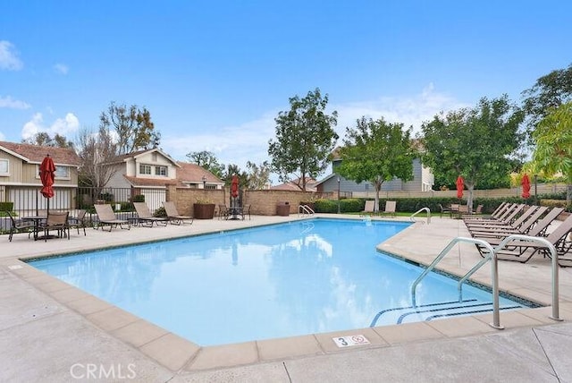 pool with a patio area and fence