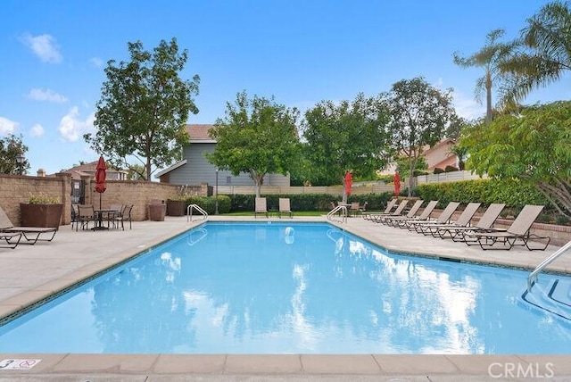 community pool with a patio and fence