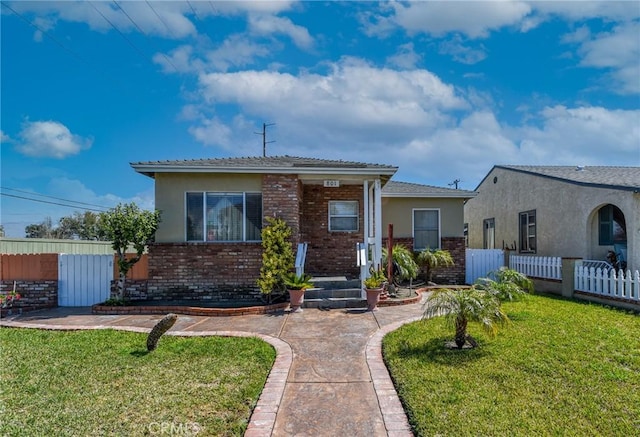 view of front of house featuring stucco siding, fence, a front lawn, and brick siding