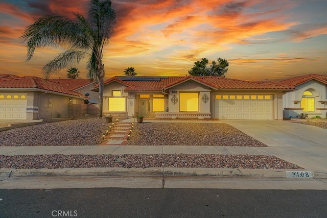 view of front facade featuring solar panels, stucco siding, a garage, driveway, and a tiled roof