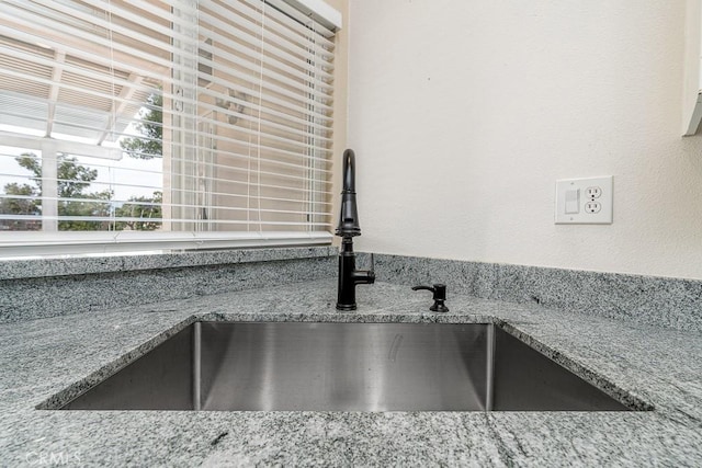 interior details featuring light stone counters and a sink