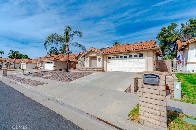 view of front of property with a garage, concrete driveway, a tile roof, a gate, and stucco siding