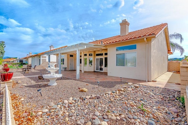 back of property featuring a tile roof, a patio, a chimney, stucco siding, and fence