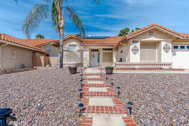 view of front of house featuring stucco siding, solar panels, a gate, fence, and a garage