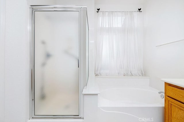 full bathroom with vanity, a shower stall, and a bath