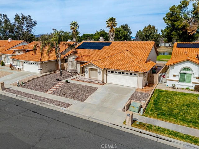 view of front of house featuring a garage, concrete driveway, a tiled roof, and solar panels