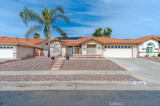 view of front of property with an attached garage, solar panels, driveway, a gate, and stucco siding