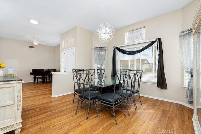 dining area with ceiling fan with notable chandelier, light wood-type flooring, visible vents, and baseboards