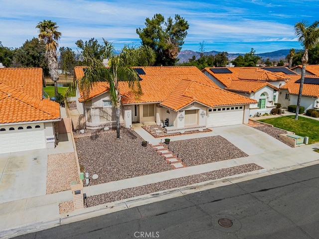 mediterranean / spanish home featuring driveway, a garage, a tile roof, fence, and a mountain view