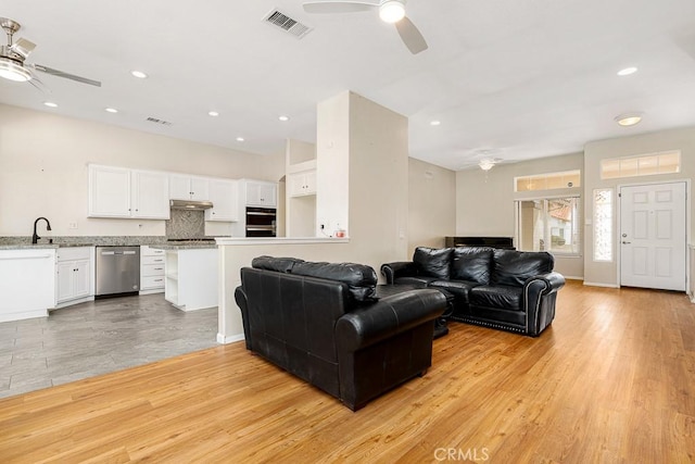 living room featuring ceiling fan, light wood-type flooring, visible vents, and recessed lighting