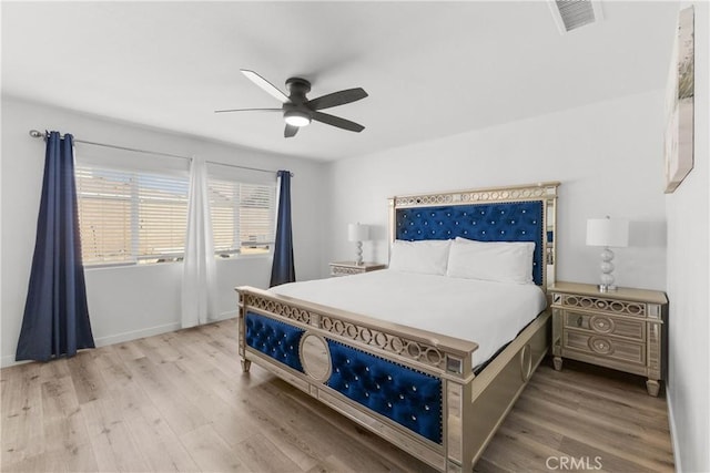 bedroom featuring baseboards, wood finished floors, visible vents, and a ceiling fan