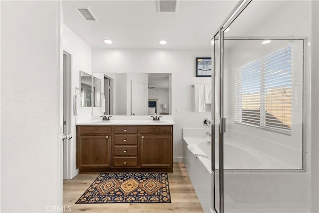 bathroom with double vanity, visible vents, a sink, and a bath