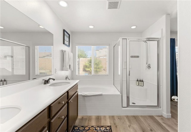 bathroom featuring a garden tub, visible vents, a sink, a shower stall, and wood finished floors