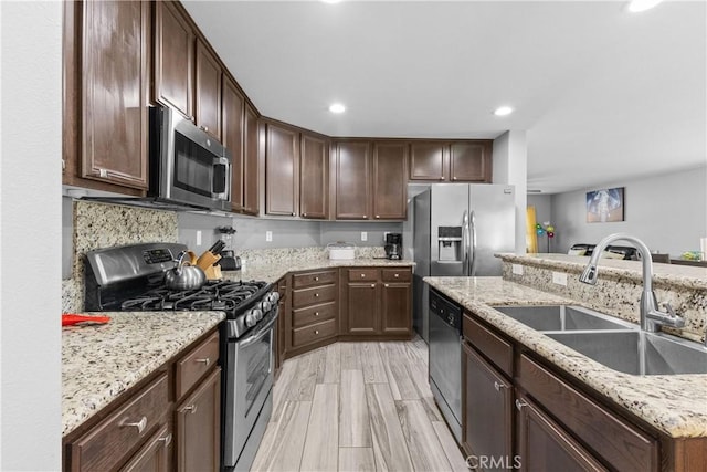 kitchen with dark brown cabinetry, stainless steel appliances, light wood-style floors, a sink, and recessed lighting