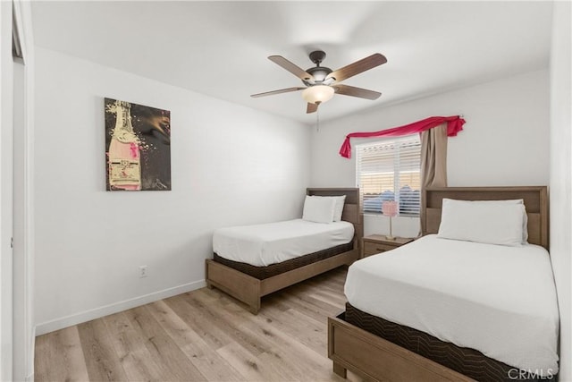 bedroom with ceiling fan, light wood finished floors, and baseboards